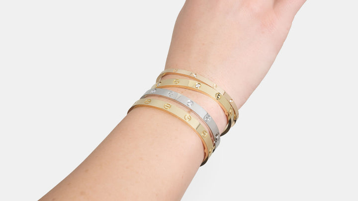 A wrist wearing four different Cartier LOVE bracelets