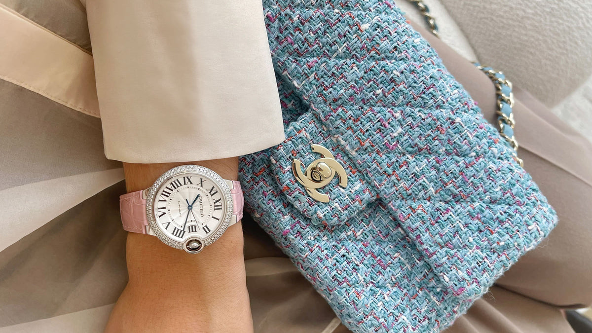A wrist with a watch and a tweed Chanel double flap atop
