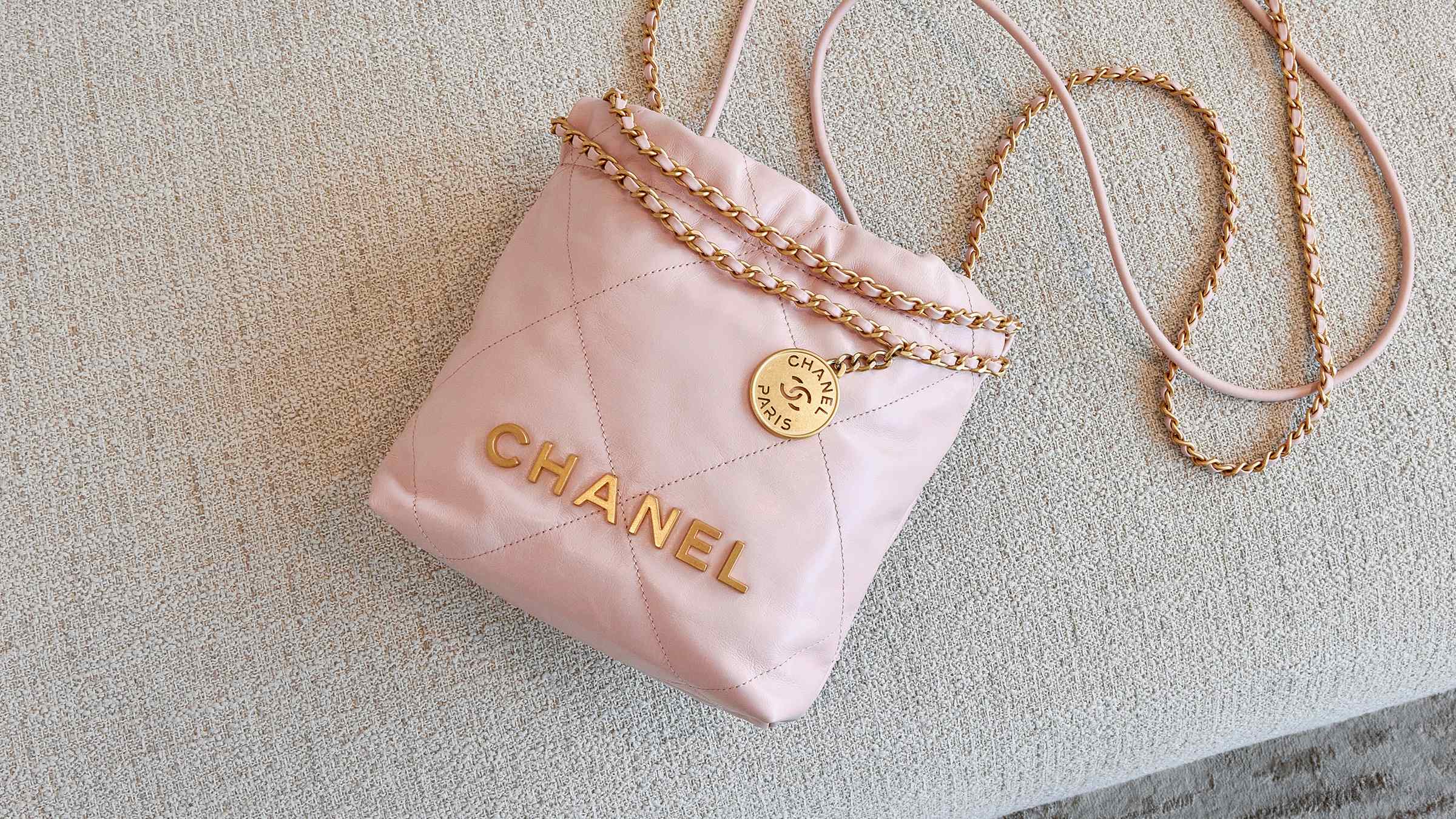lifestyle image of pink mini chanel 22 bag laying on the couch FASHIONPHILE