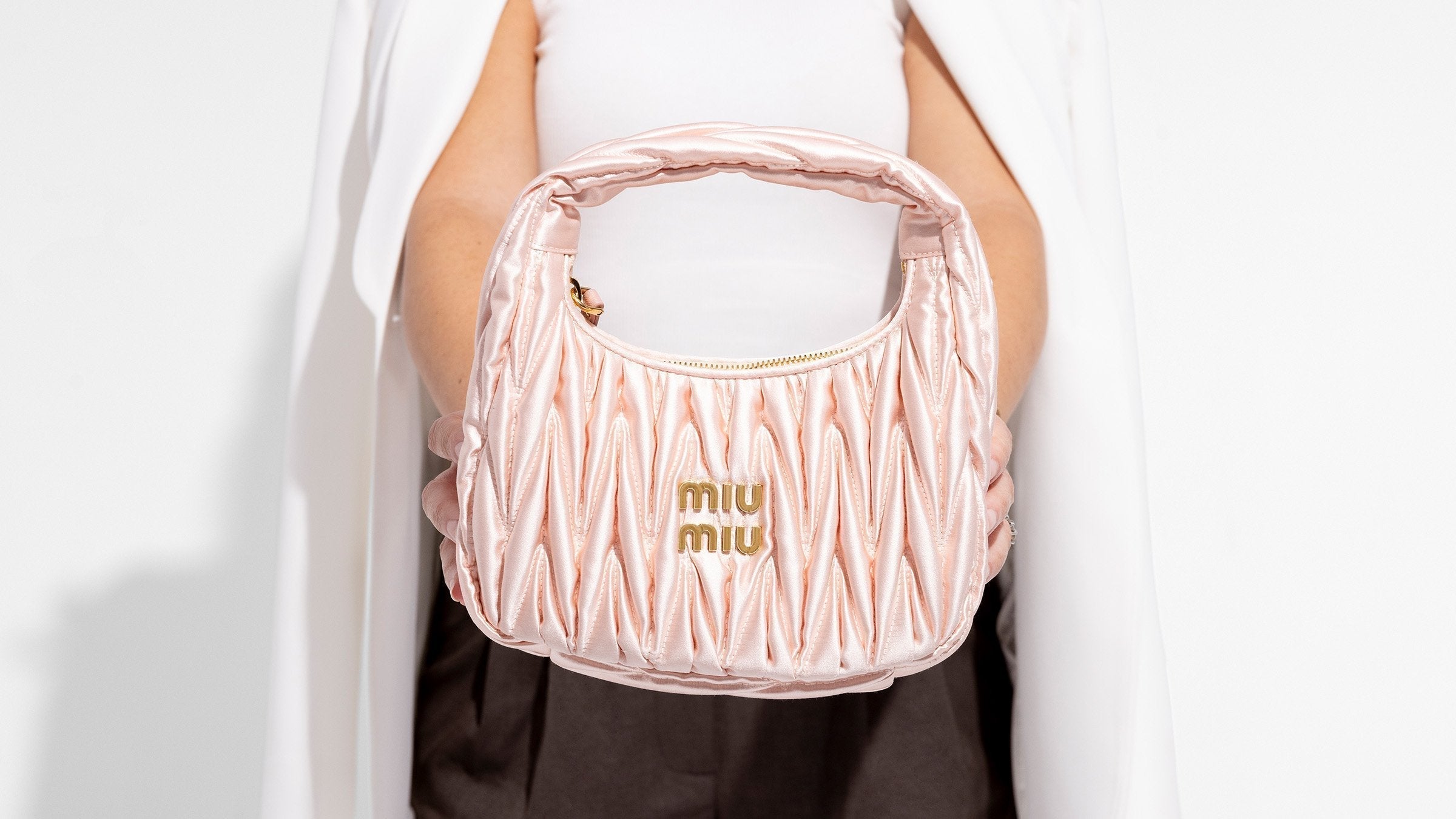 girl holding satin miu miu mini wander bag in pink by fashionphile