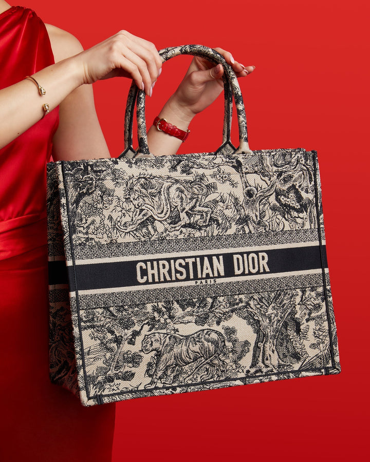 studio image of model wearing red holding Dior book tote with tiger embroidery for Lunar New Year at FASHIONPHILE