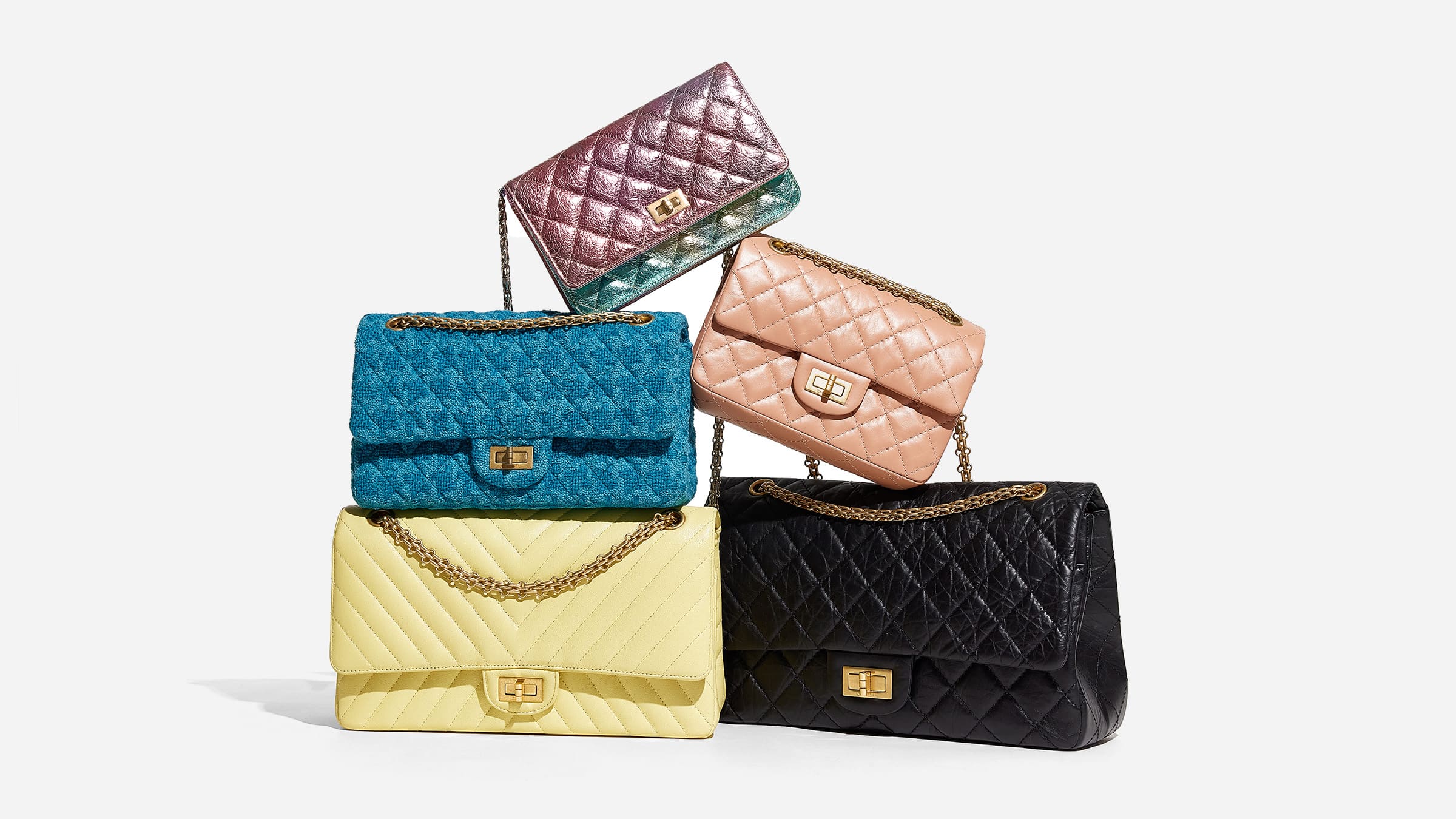 group of chanel 2.55 reissue flap bags in different colors and sizes stacked on top of one another by FASHIONPHILE