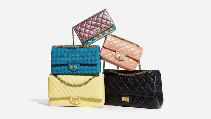 group of chanel 2.55 reissue flap bags in different colors and sizes stacked on top of one another by FASHIONPHILE