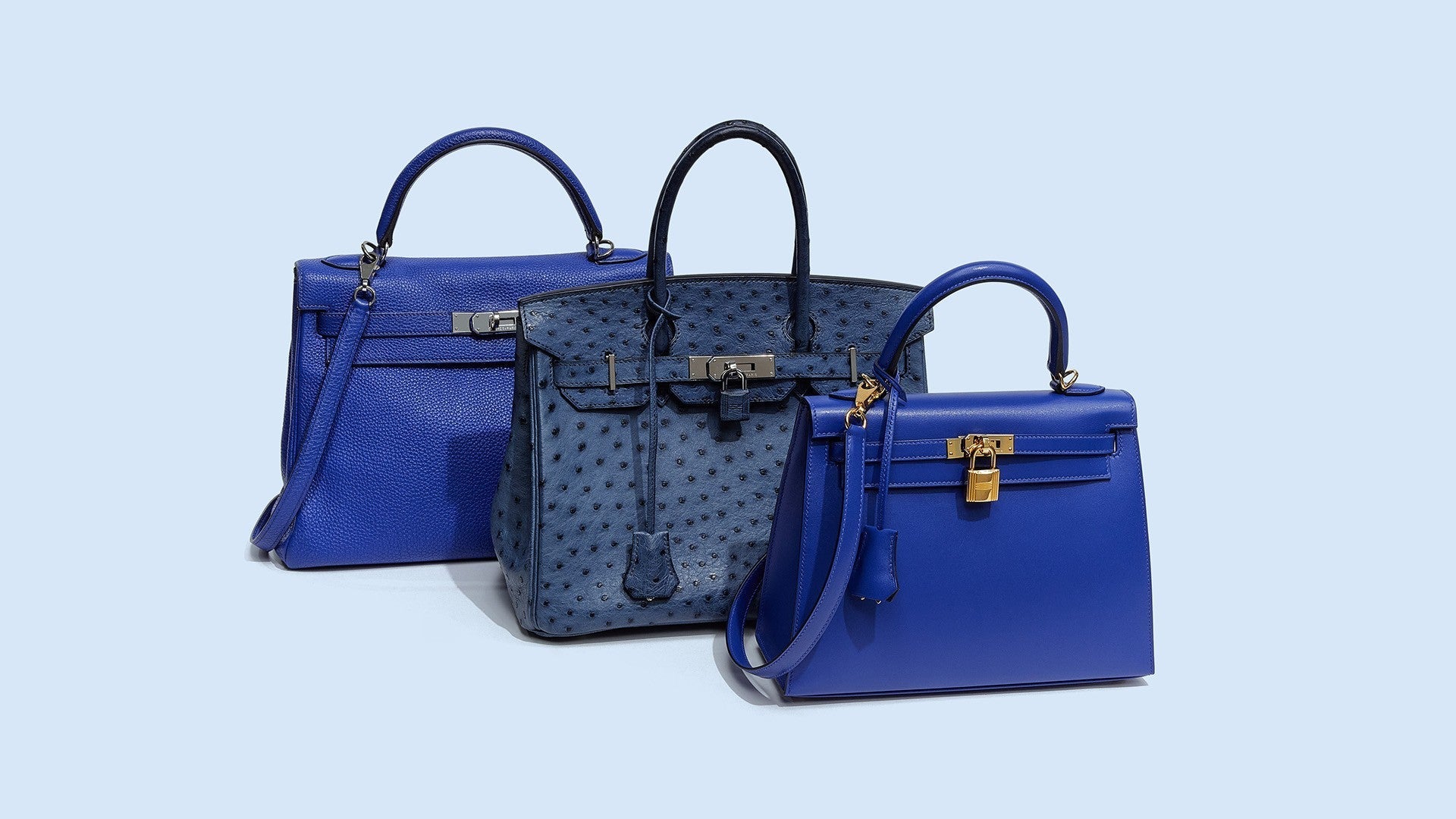 studio image of blue Hermes bags grouped together on light blue background FASHIONPHILE