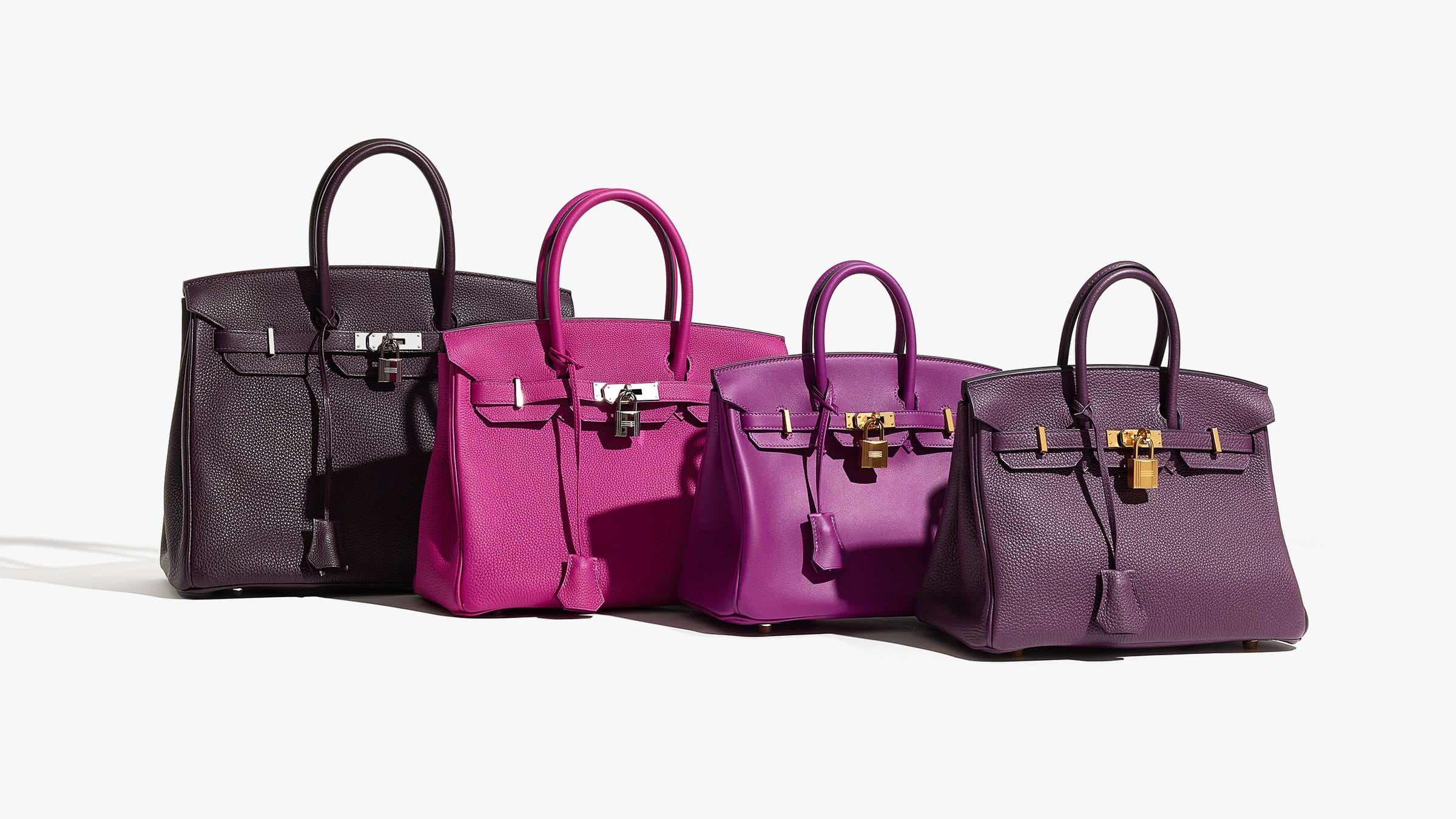 this is a photo of four purple hermes birkin bags lined up next to each other by FASHIONPHILE
