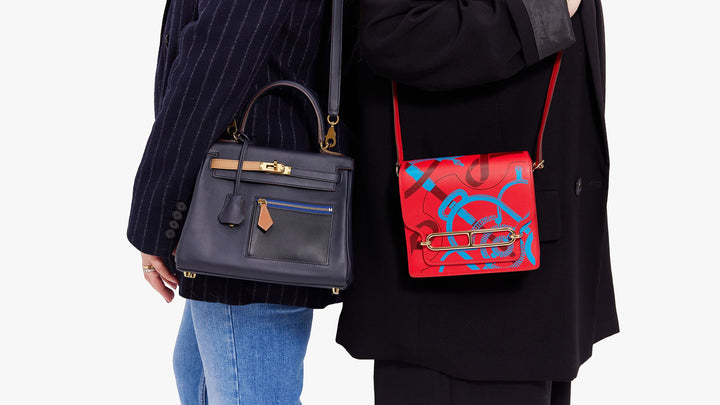 models wearing hermes bags side by side, one model wearing a rare hermes kelly retourne bag in black and blue and another model wearing a special edition hermes Mini Sac Roulis in red and blue by FASHIONPHILE