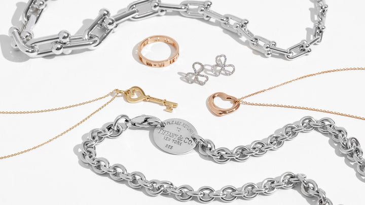 this is a studio laydown image by FASHIONPHILE of different tiffany and co jewelry pieces styled together on a white background
