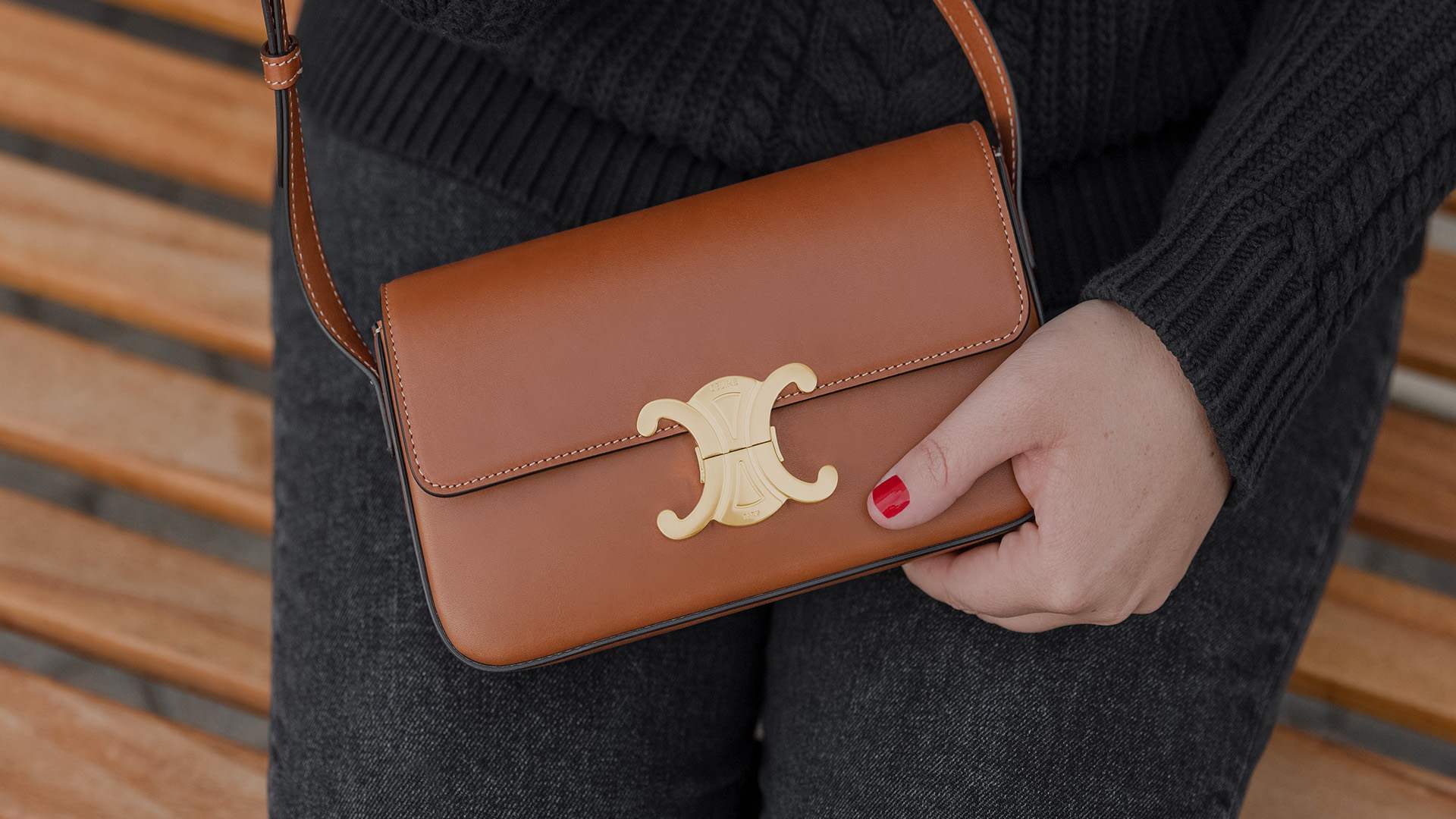 lifestyle image close up of Celine triomphe bag held by model wearing cable knit sweater and jeans