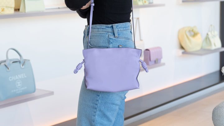 image of shopper wearing a lavender purple loewe flamenco clutch as a crossbody inside the FASHIONPHILE San Diego Flagship