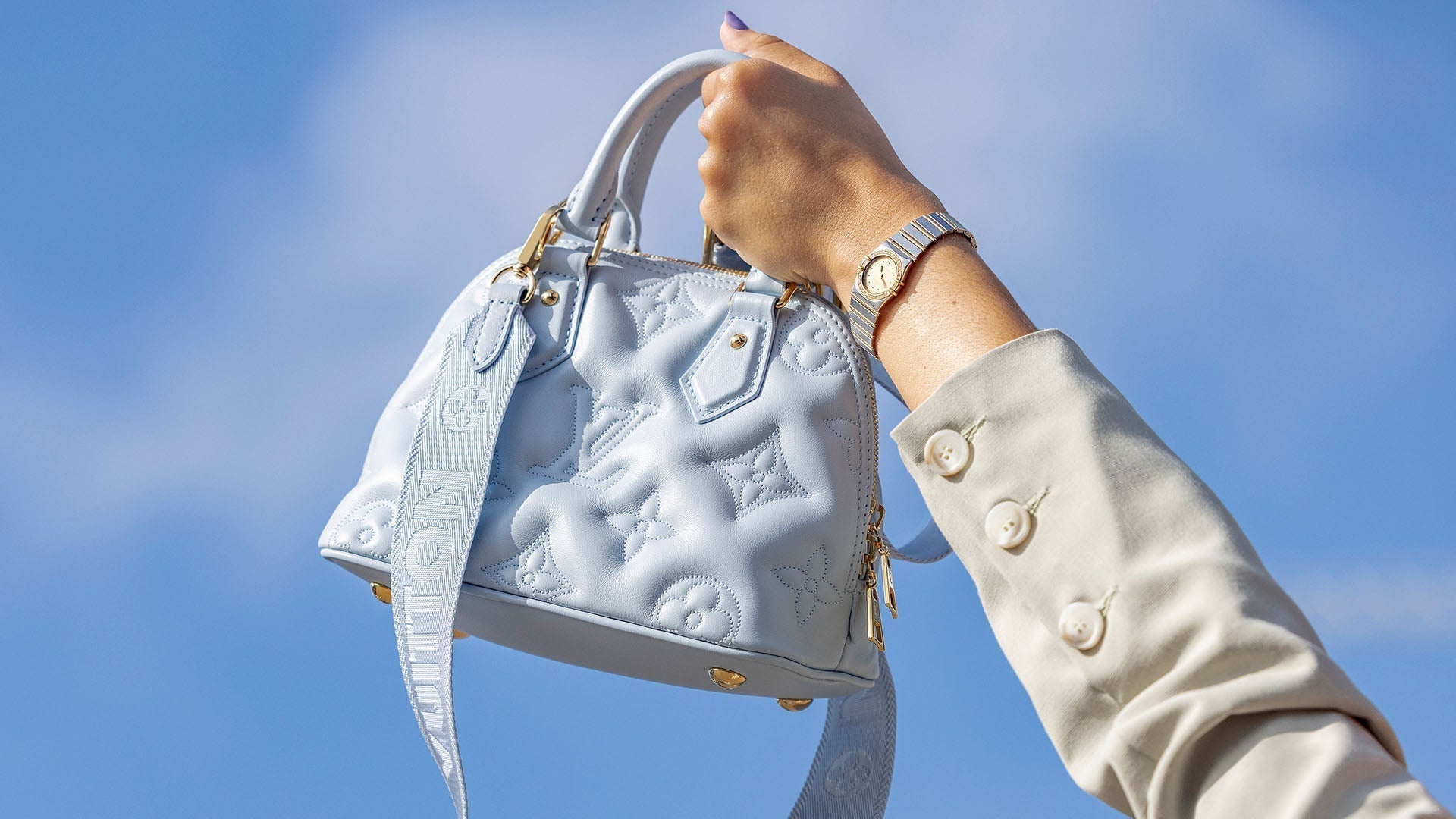 lifestyle image of louis vuitton alma bag held up in the sky FASHIONPHILE