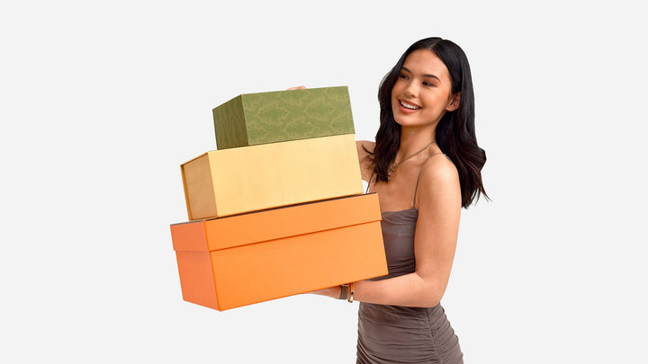 model holding stack of designer boxes including hermes, fendi, and gucci by FASHIONPHILE
