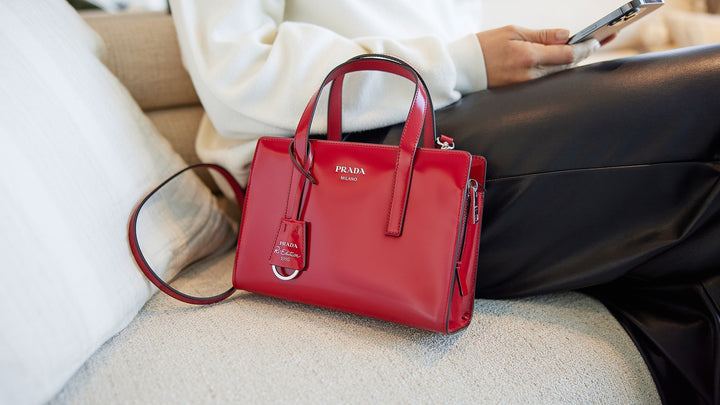 lifestyle image of red leather prada bag on couch next to FASHIONPHILE shopper