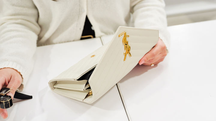 A FASHIONPHILE Saint Laurent brand expert authenticates a Saint Laurent Monogram Chain Wallet at her station.