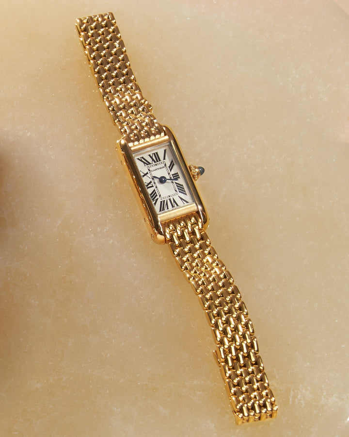 lay down image of yellow gold cartier watch on marble FASHIONPHILE