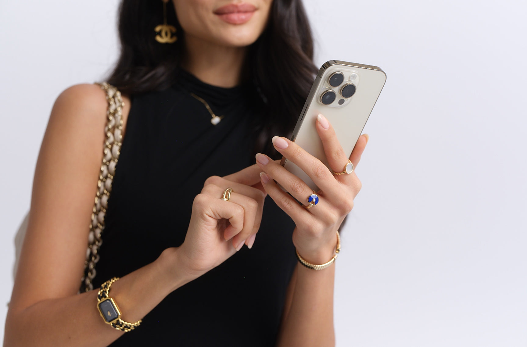 a woman wearing a black sleeveless dress and holding an iPhone scrolling on the screen